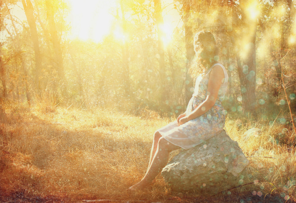 32875194 - surreal blurred background of young woman sitting on the stone in forest. abstract and dreamy concept. image is textured and retro toned