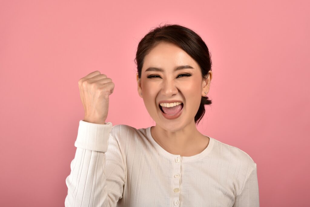 Asian woman feeling happy and excited on accomplish success on pink background, Portrait of smiling winner girl celebrating use for advertising.